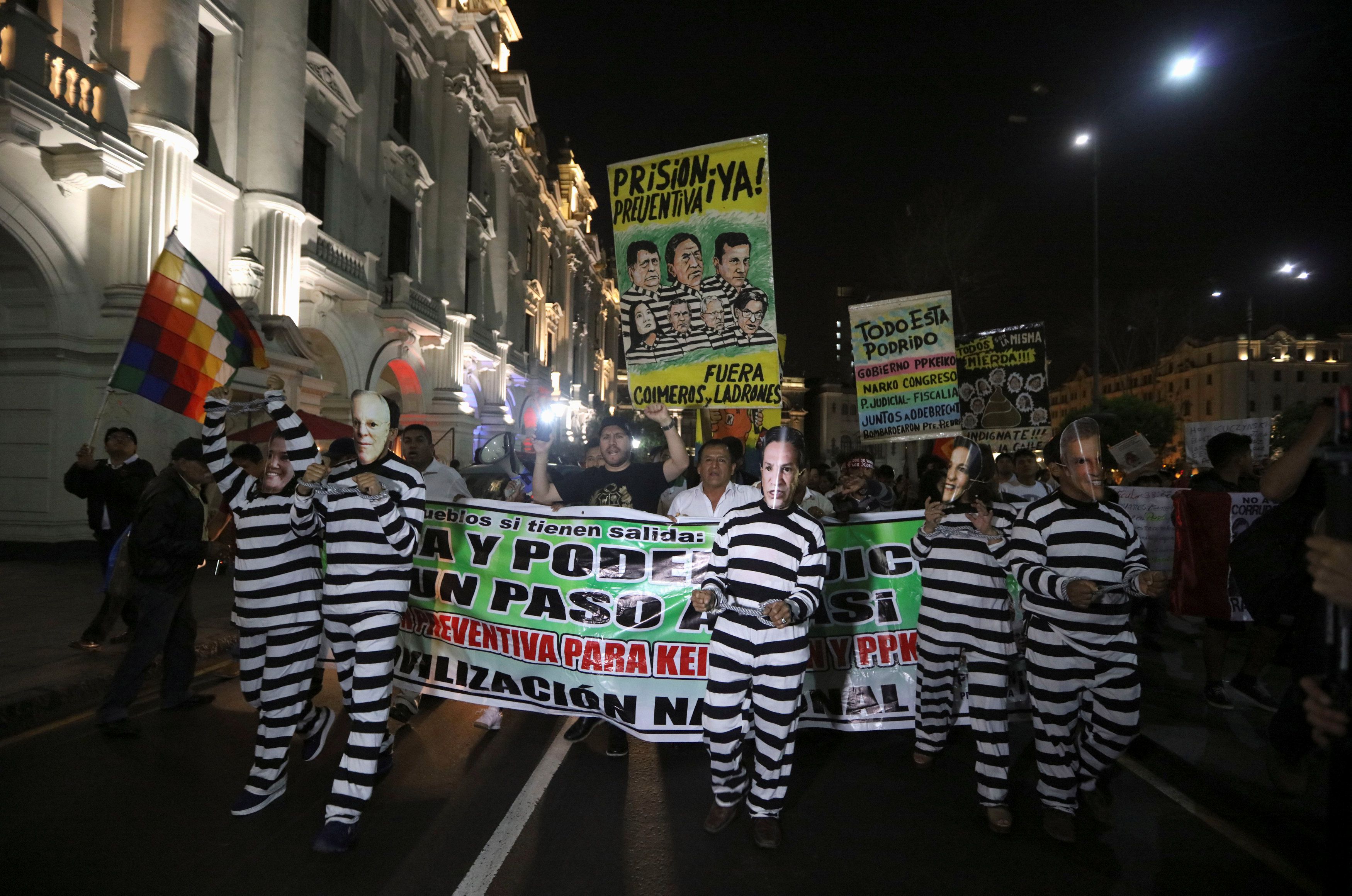 Demonstrators dressed in mock prison outfits and wearing face masks made with the photographs of Peru's President Kuczynski and fellow politicians, protest with others against the government and the country's political institutions, in Lima