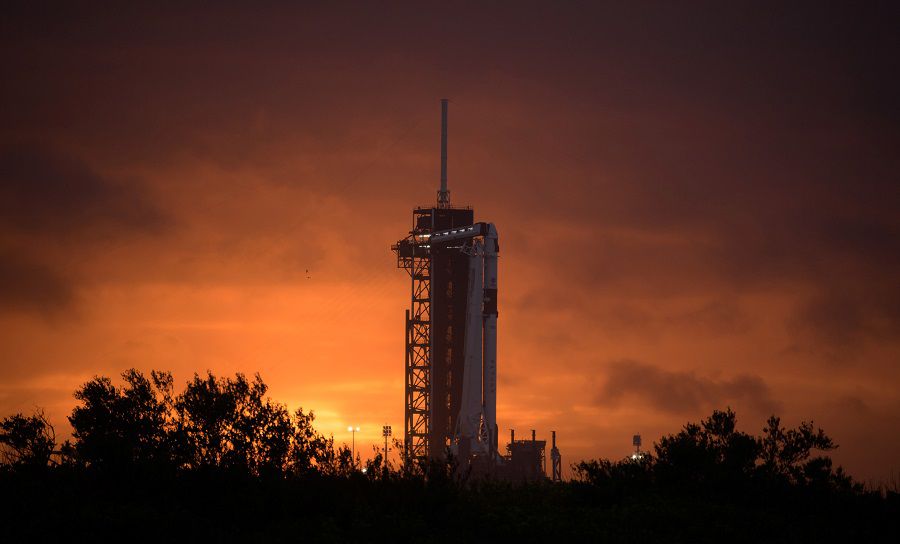 The sun sets behind a SpaceX Falcon 9 rocket with the company's Crew Dragon spacecraft onboard