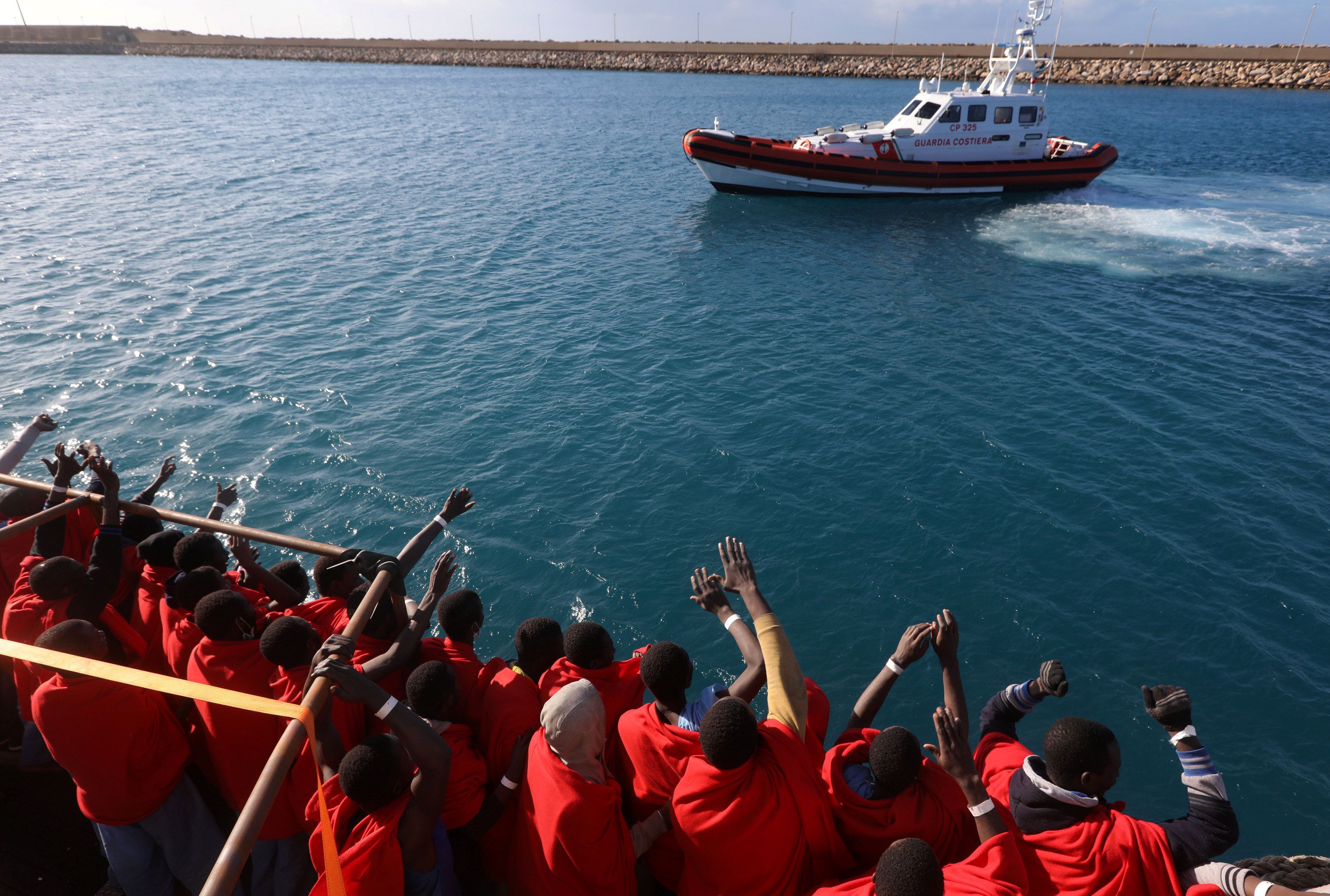 Migrants celebrate as they arrive in Italy on board the Golfo Azzurro rescue vessel after they were rescued in Mediterranean Sea