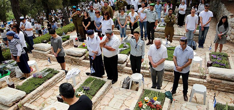 Israeli mourners observe two minutes of silence near graves during a