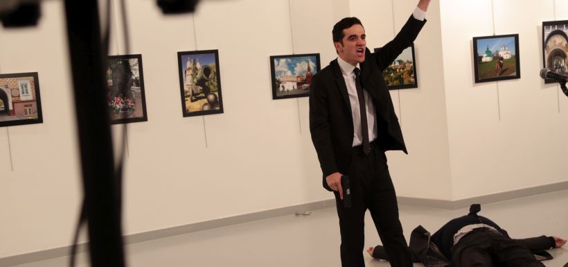 A man gestures near to the body of a man at a photo gallery in Ankara