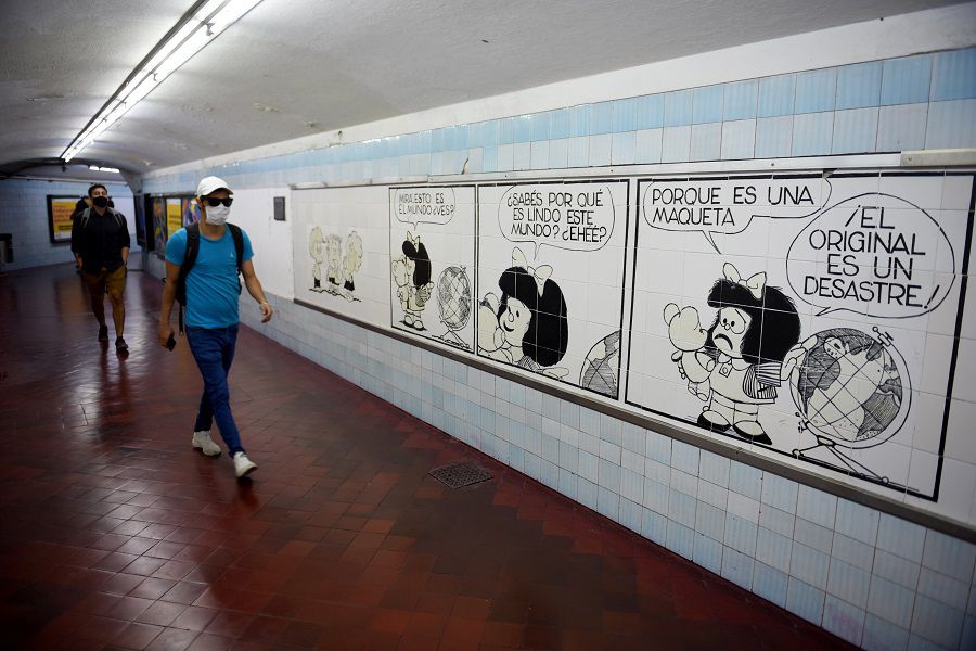 People walk past a painting depicting a comic strip of Mafalda, created by cartoonist Joaquin Salvador Lavado, also known as Quino, who died today at the age of 88, in Buenos Aires