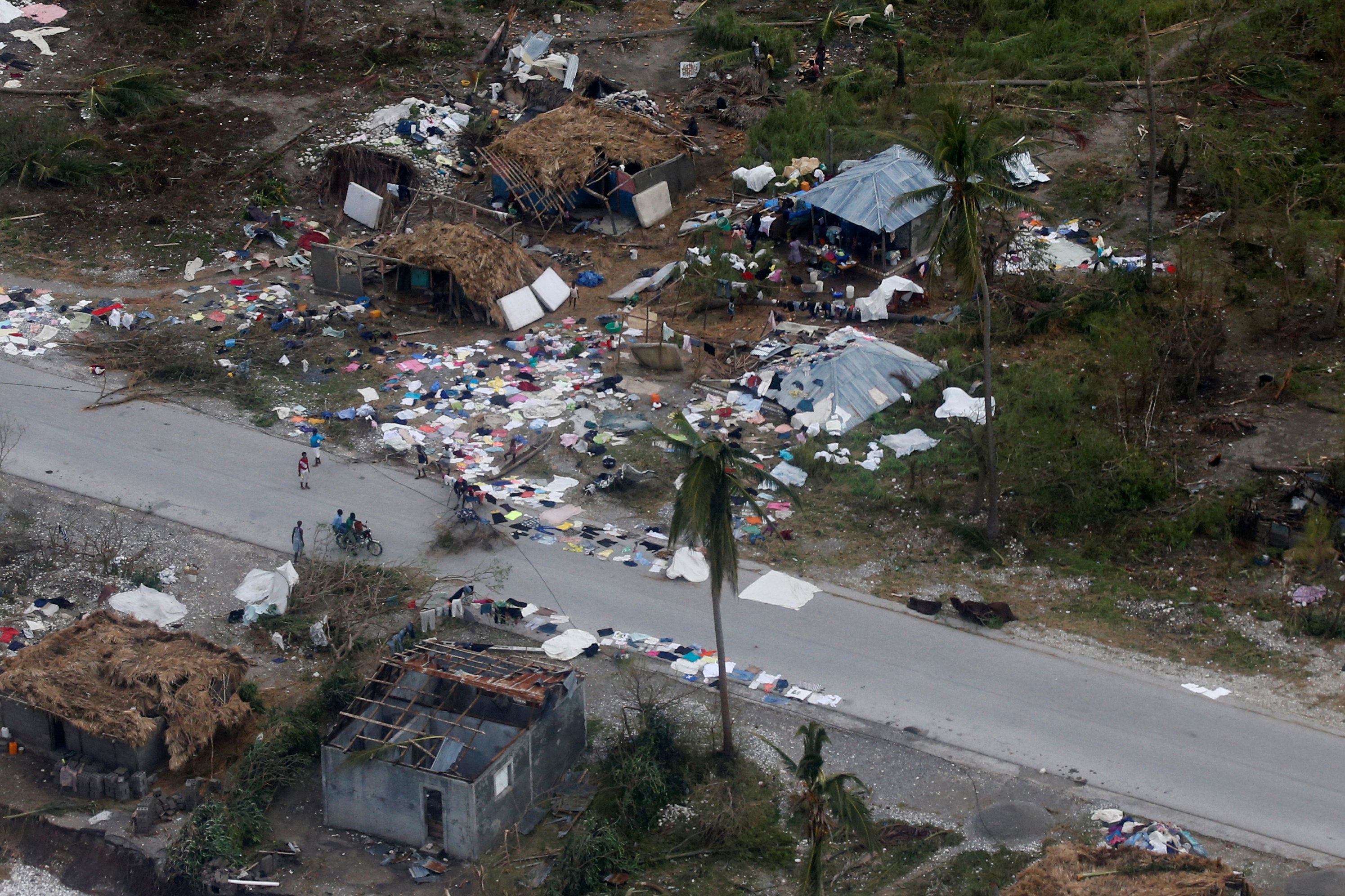 People walk down the street next to destroyed houses after Hurricane Matthew passes Jeremie, Haiti