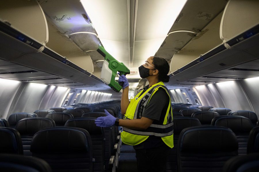 Worker demonstrates use of an electrostatic disinfectant sprayer on United Airlines plane at IAH George Bush Intercontinental Airport in Houston