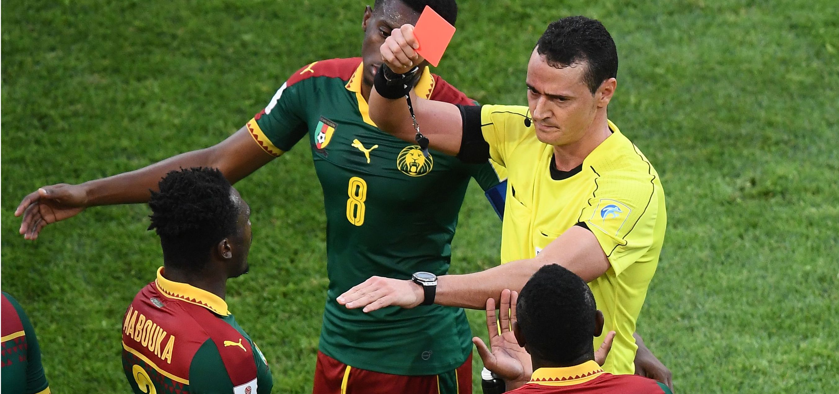 Colombian referee Wilmar Roldan (R) gives a red card to Cameroon's de