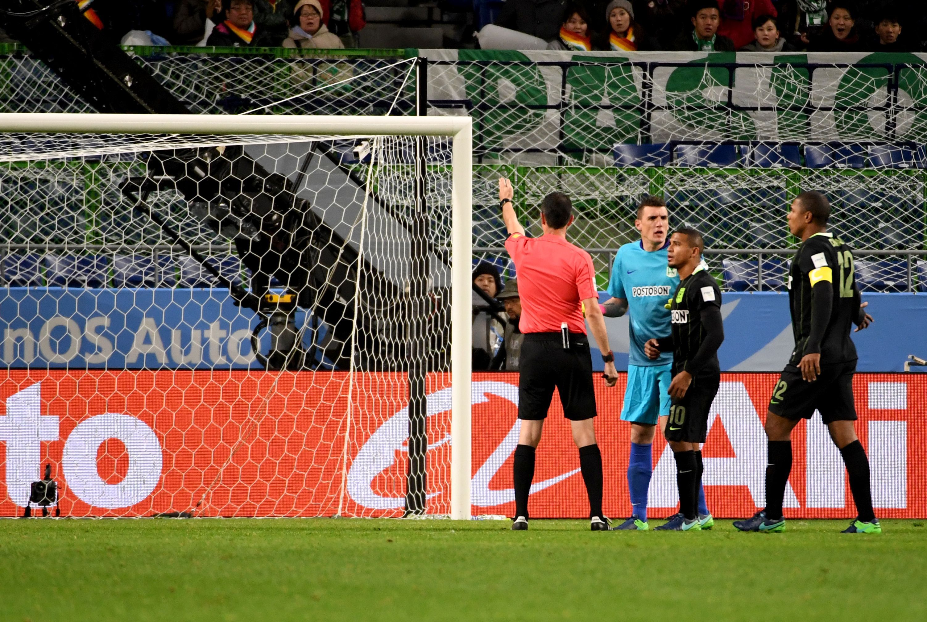 A referee (L) points to a penalty kick after speaking with the video