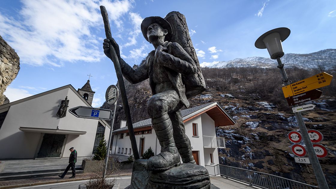 A man walks past a statue of a local smuggler in southern Swiss villa