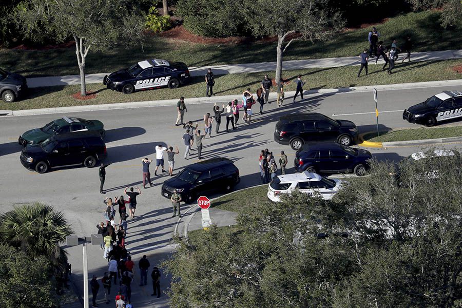 Students hold their hands in the air as they are evacuated by police