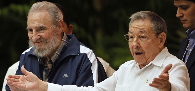 Cuba's President Raul Castro reacts next to his brother and former President Fidel Castro during closing ceremony of Cuban communist congress in Havana