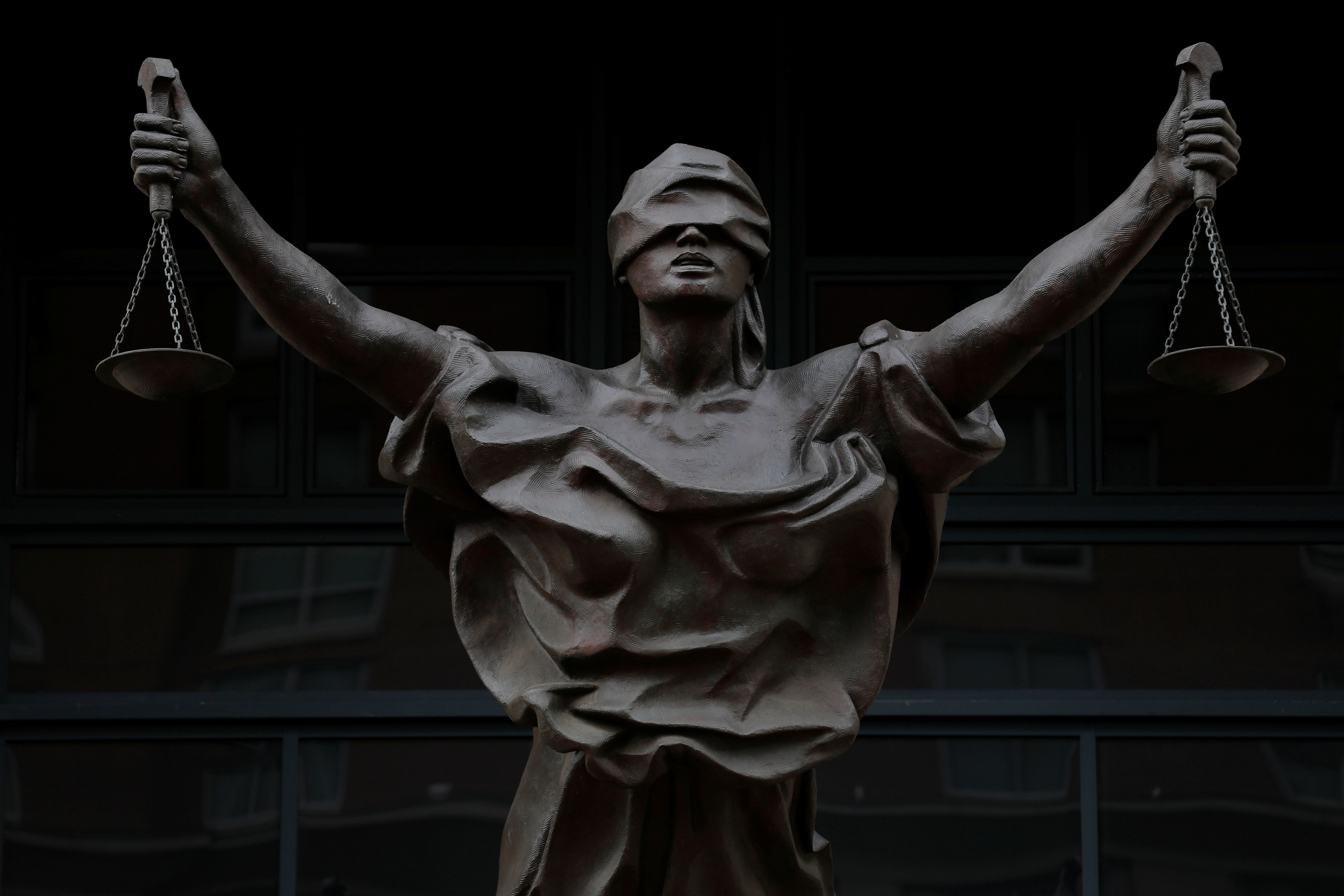 A bronze statue titled "Justice Delayed, Justice Denied" depicting a figure of Justice is seen on the Albert V. Bryan United States Courthouse in Alexandria, Virginia