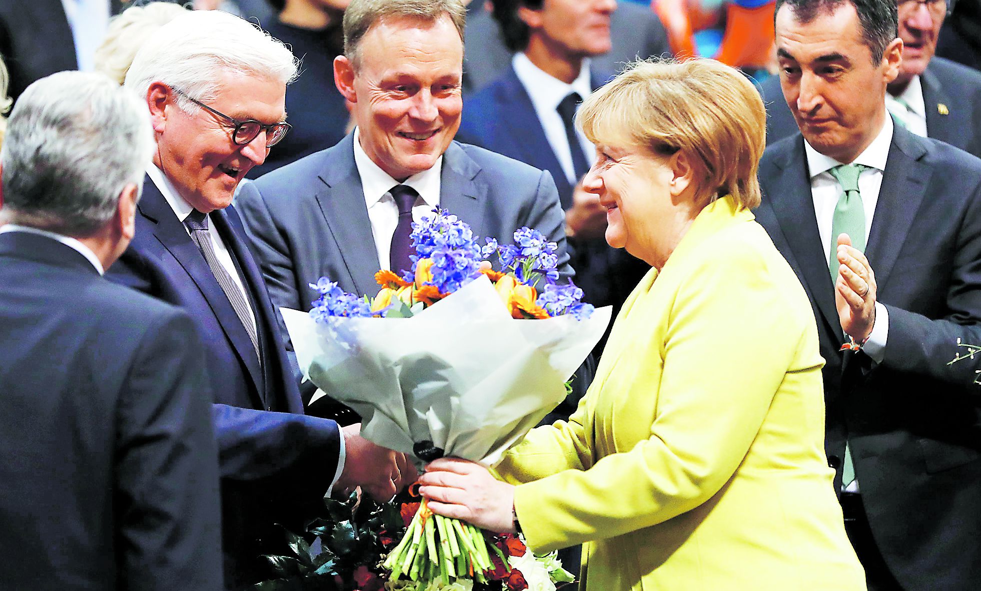 German Chancellor Angela Merkel (R) hands over flowers to new elected