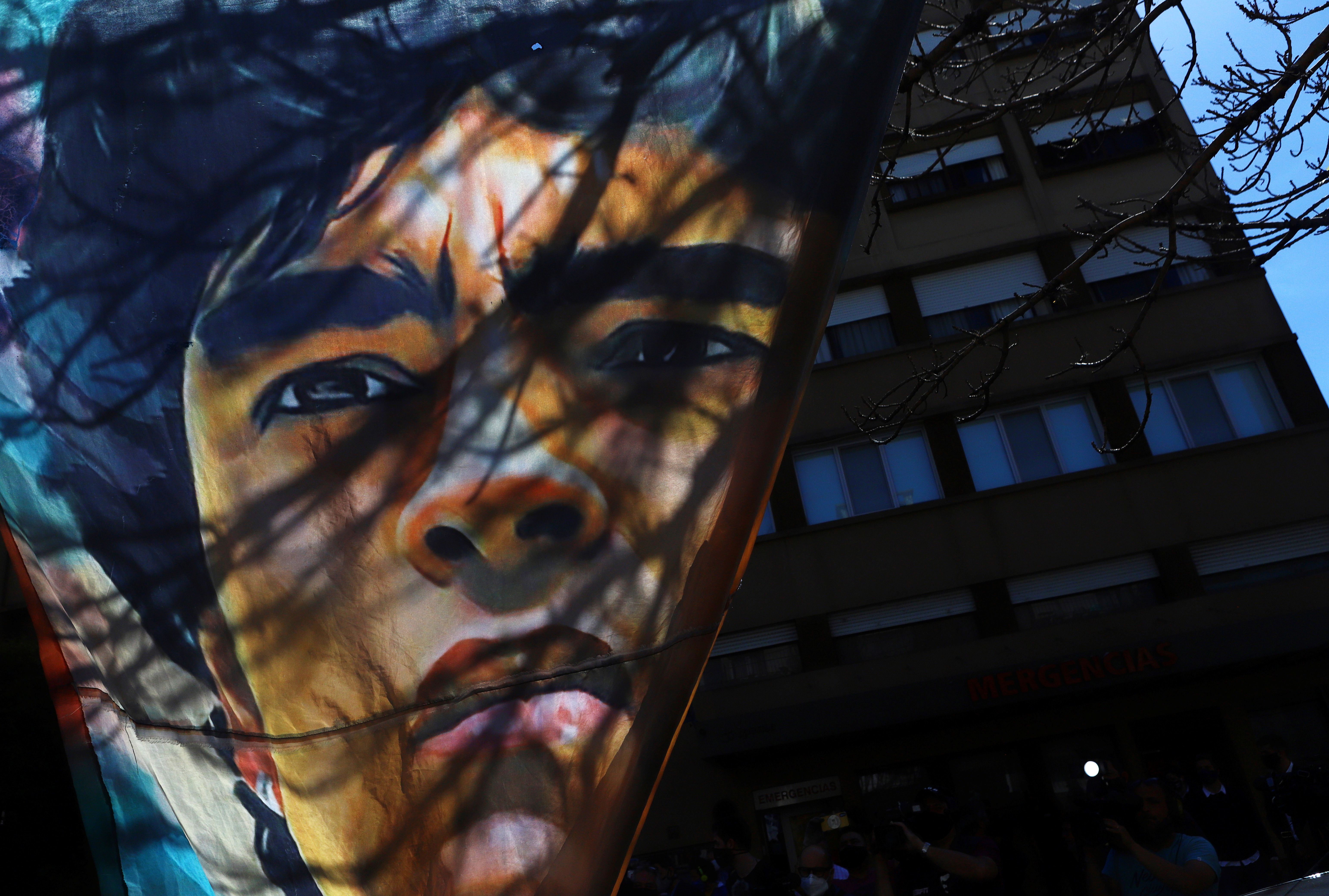 A banner with a portrait of Argentine soccer great Diego Maradona hangs outside the hospital where he was admitted due to being anemic and dehydrated, according to his personal physician, in Buenos Aires