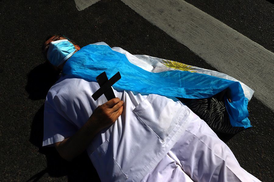 A health worker lies on the floor wrapped in the national flag during a tribute in honour of fellow workers who died during the coronavirus disease (COVID-19) outbreak, in Buenos Aires