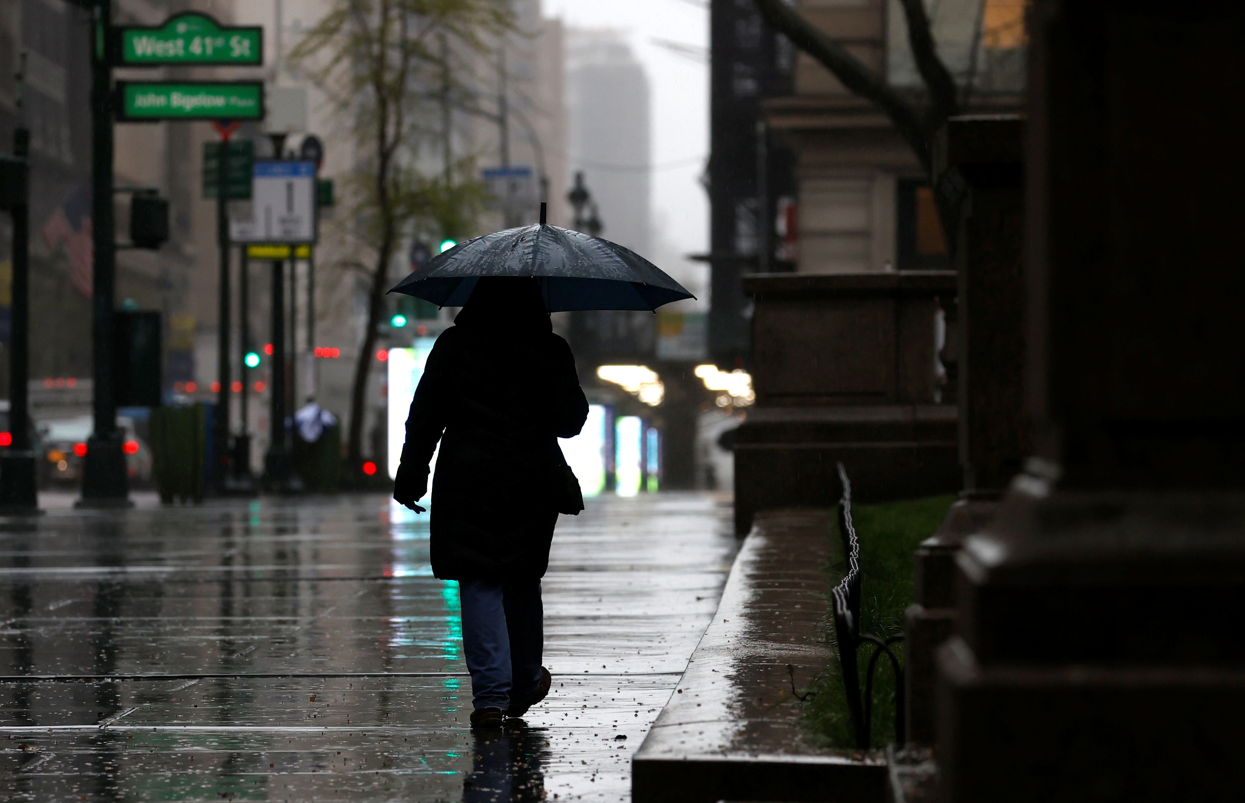 Woman walks in heavy rain and high winds on 5th Avenue during outbreak of coronavirus disease (COVID-19) in New York