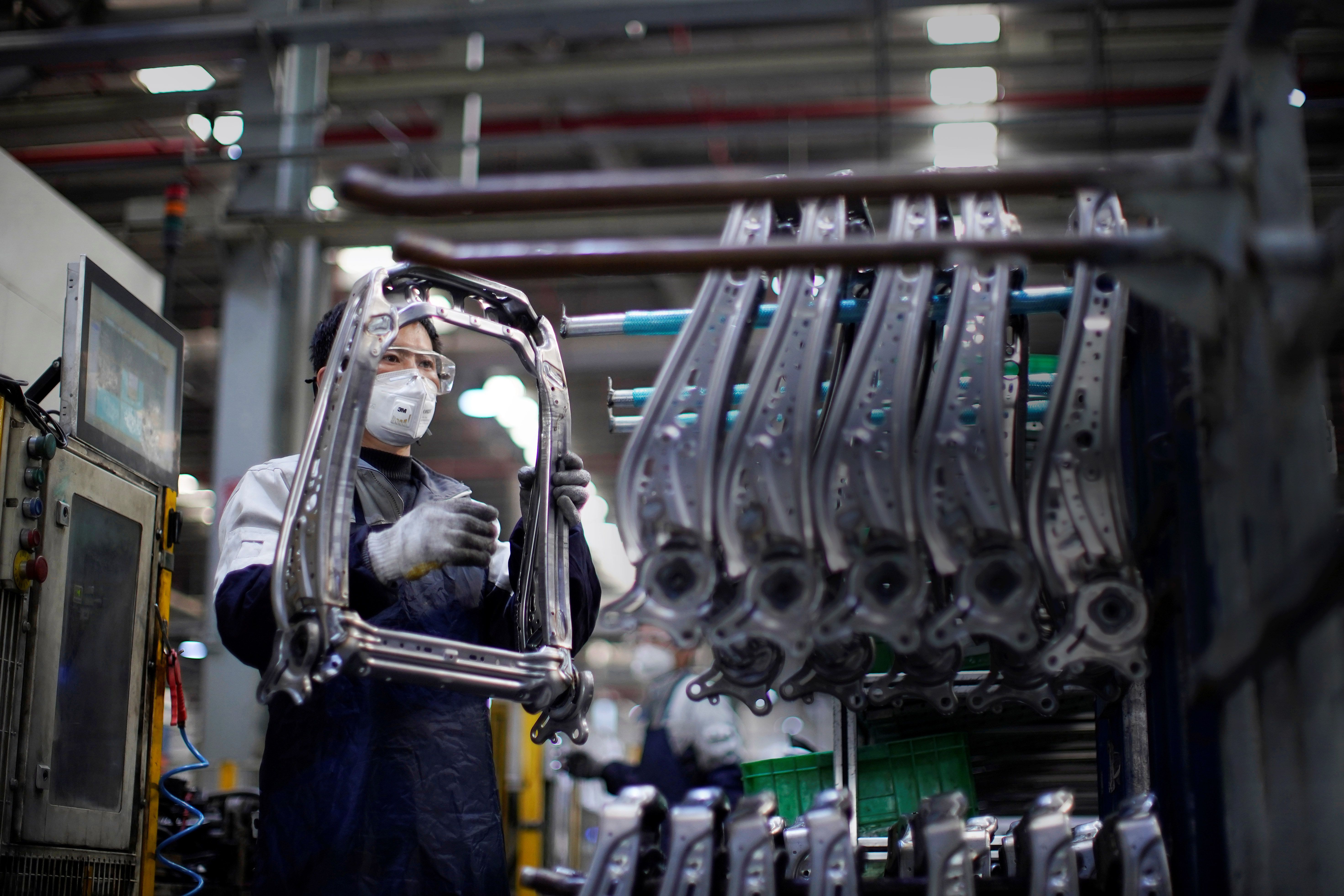 Employee wearing a face mask works on a car seat assembly line at Yanfeng Adient factory in Shanghai