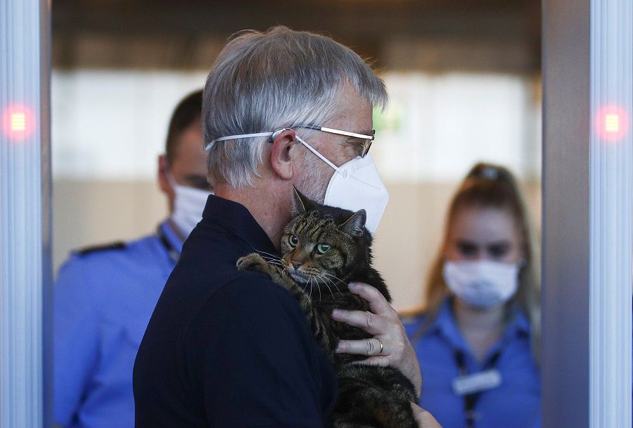 A man carrying a cat walks past security control at the Vienna International Airport in Schwechat