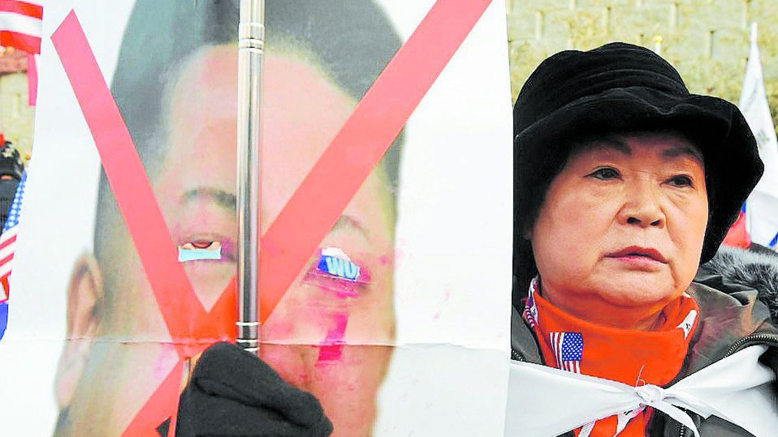 An anti-North Korea protester holds a damaged picture of North Korean