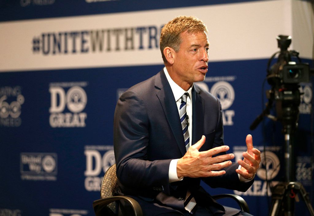 Troy Aikman, left, and Daryl Moose Johnston sign footballs for