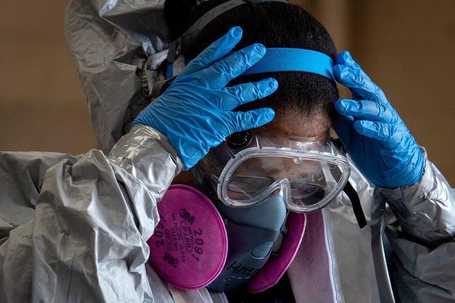 E.M.T. Tiffanni Brown removes her protective gear after decontaminating the suit at the Lakeview Firehouse in Paterson. Brown