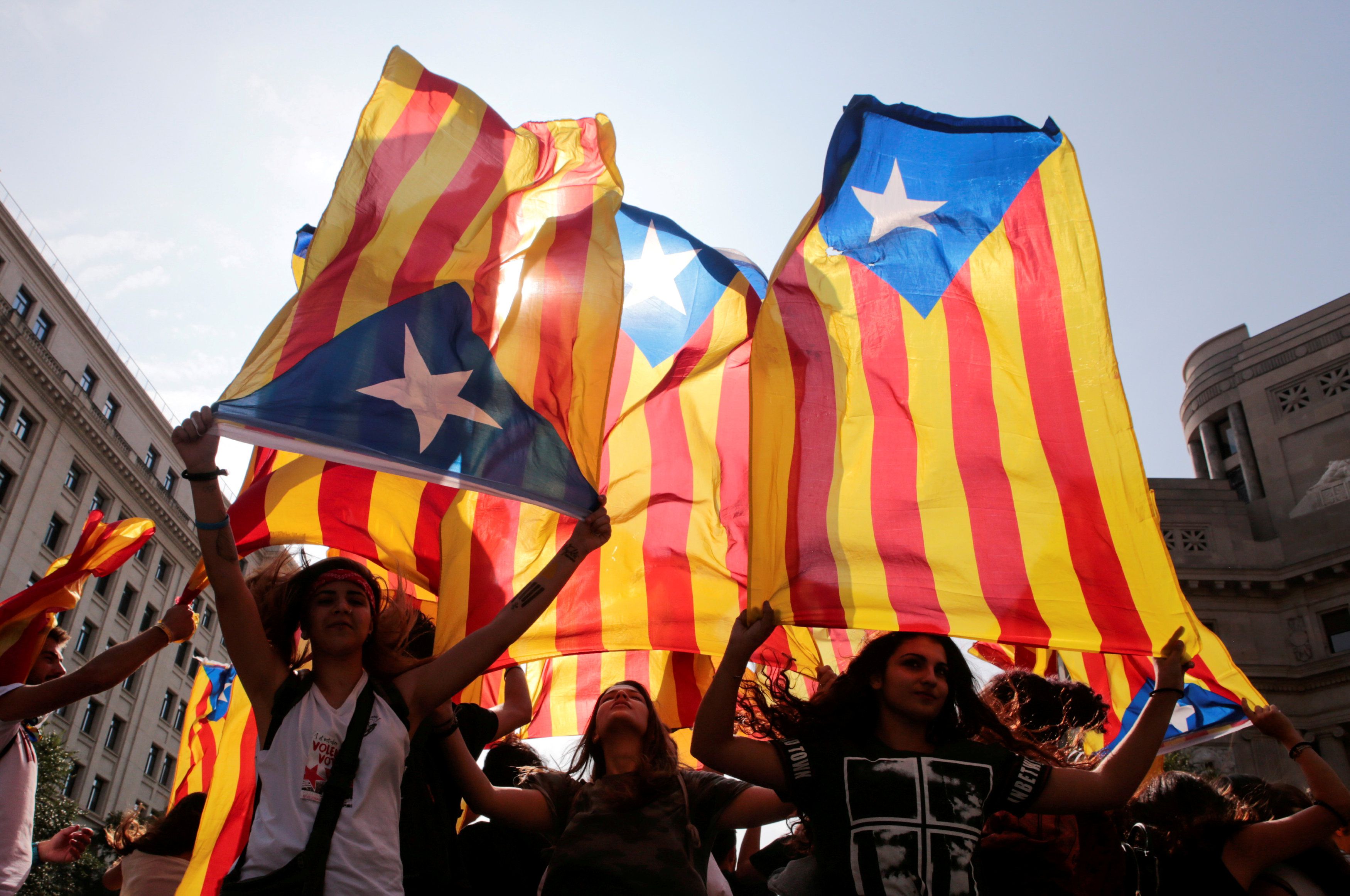 People hold on to Catalan separatist flags on top of an air vent during a demonstration two days after the banned independence referendum in Barcelona