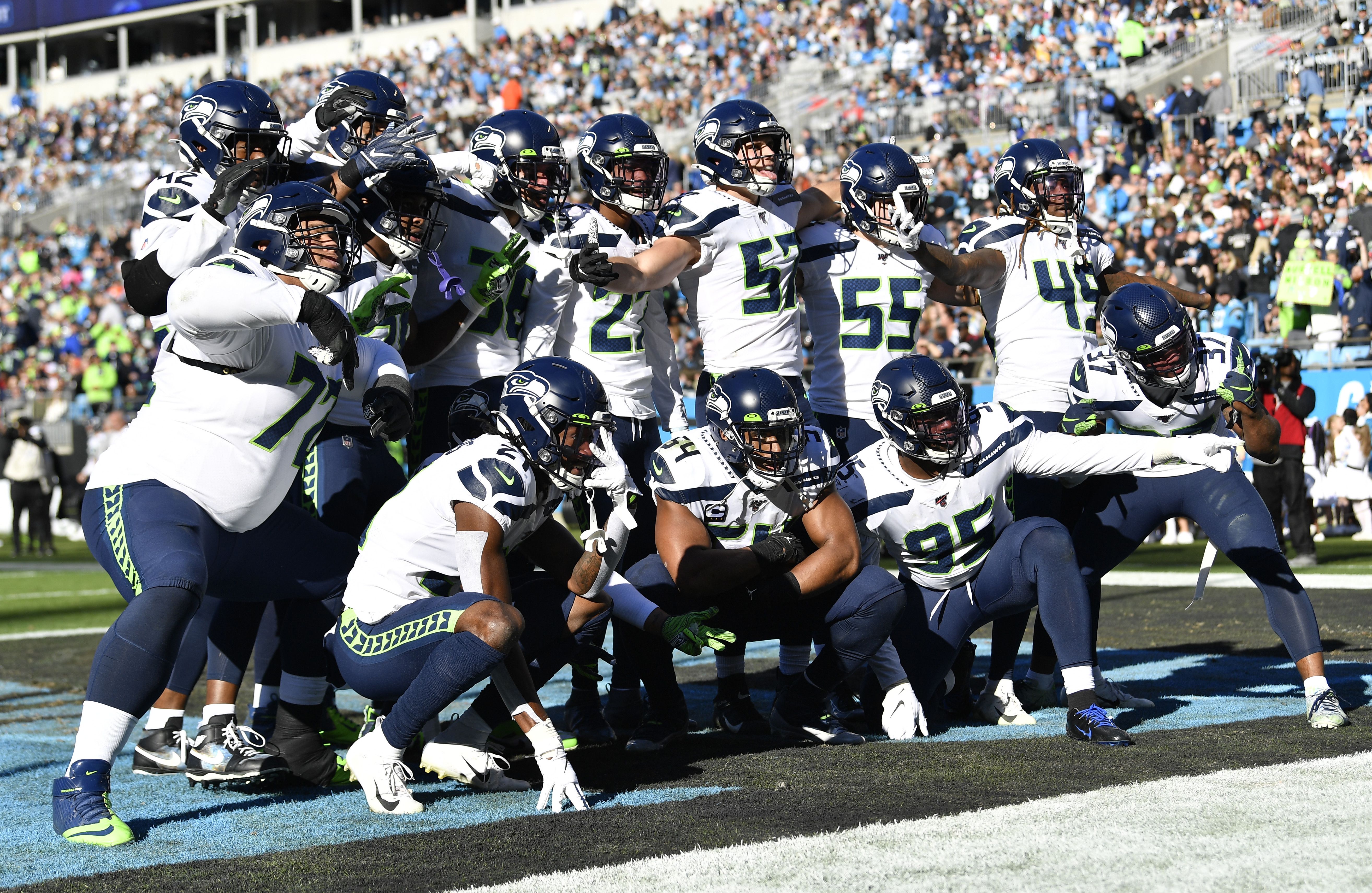 Seattle Seahawks quarterback Russell Wilson (3) hands pff to running back  Chris Carson (32) during the second half of an NFL football game against  the Carolina Panthers in Charlotte, N.C., Sunday, Dec.