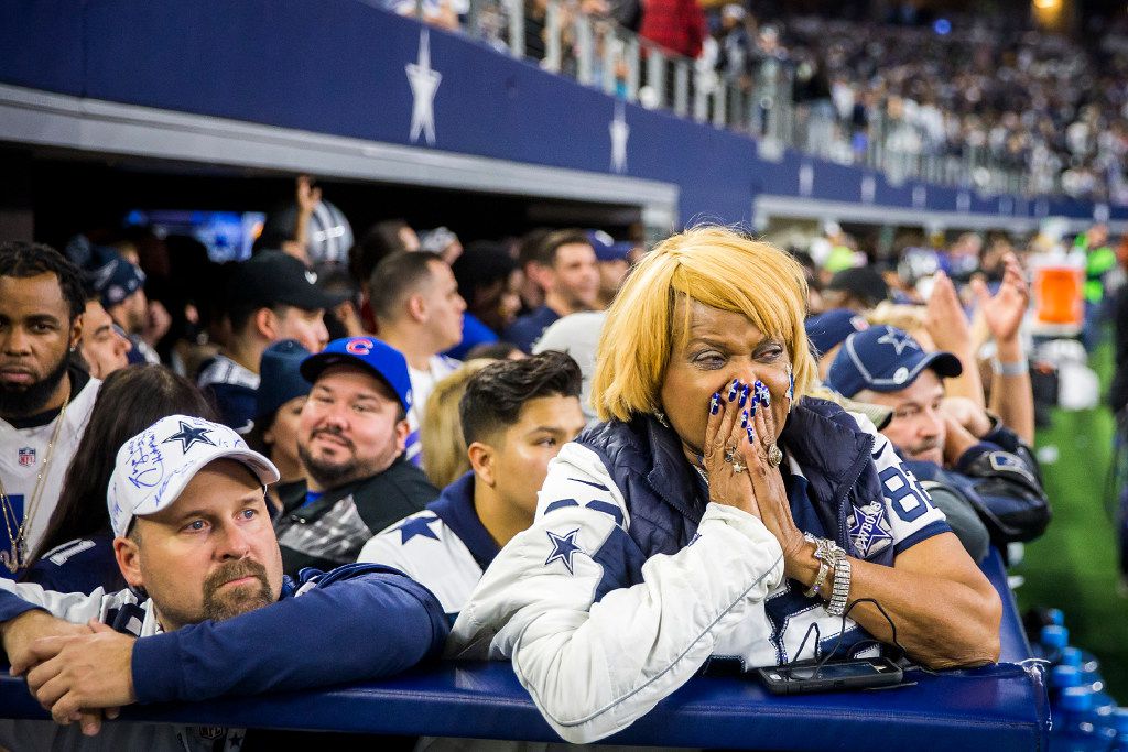 Two Dallas Cowboys fans are decked out in Cowboys gear and orange