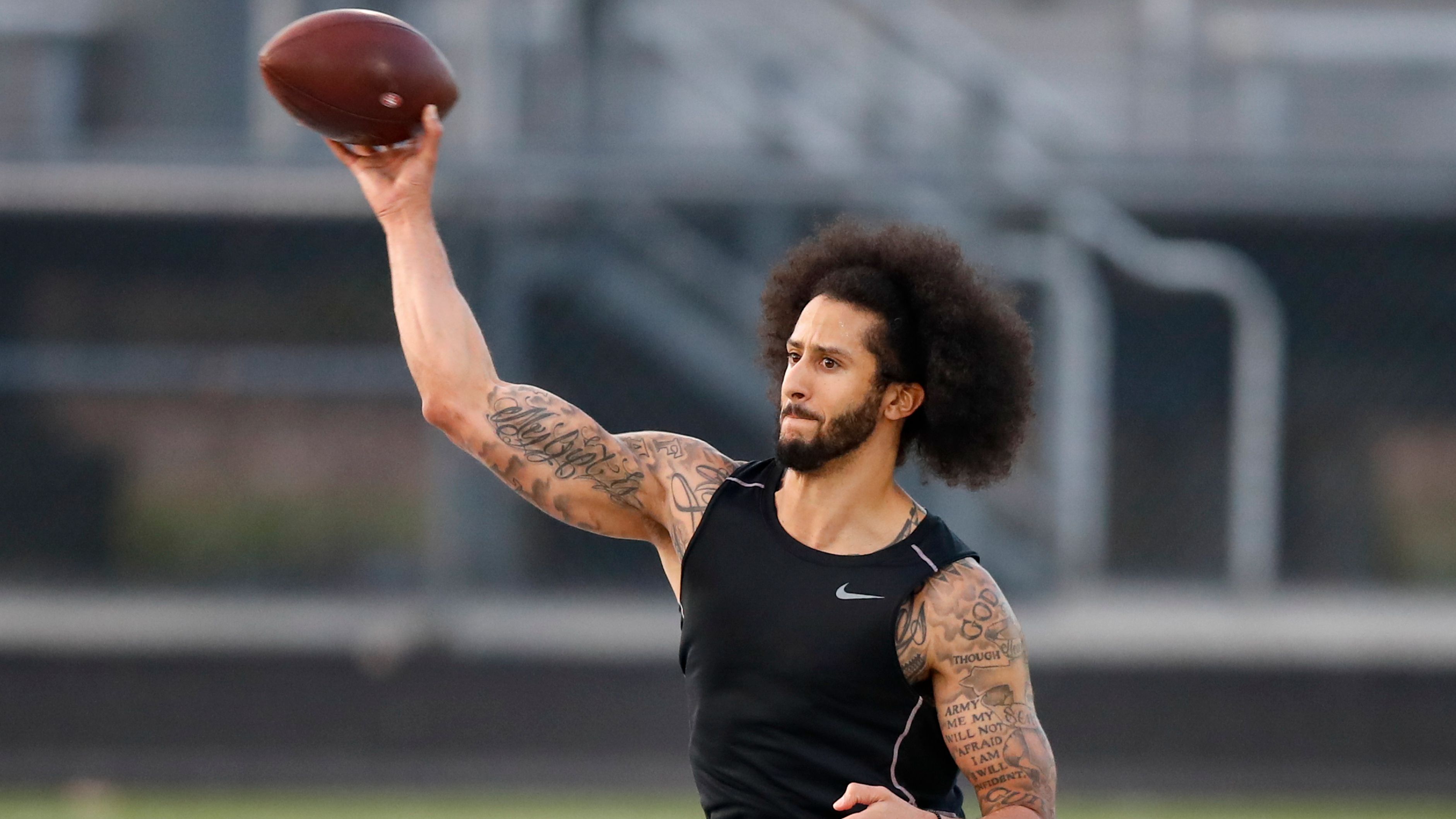 A protester holds an American flag and a sign outside of the Atlanta  Falcons' training facility where free agent quarterback Colin Kaepernick  was set to workout for NFL football scouts, Saturday, Nov.