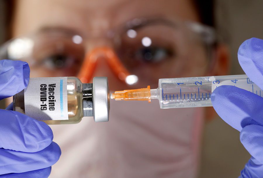 FILE PHOTO: A woman holds a small bottle labeled with a "Vaccine COVID-19" sticker and a medical syringe in this illustration. FILE PHOTO: A woman holds a small bottle labeled with a "Vaccine COVID-19" sticker and a medical syringe in this illustration taken April 10, 2020. REUTERS/Dado Ruvic/Illustration/File Photo