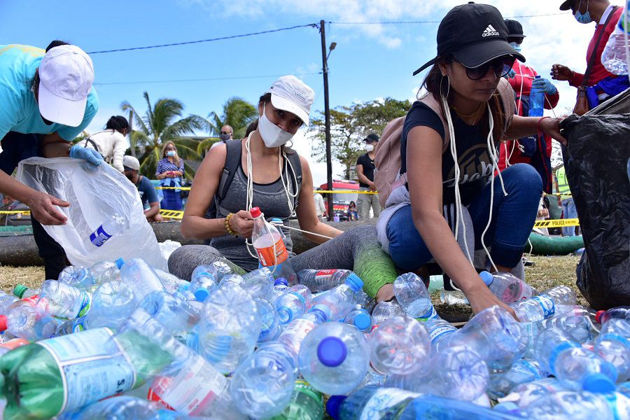 Volunteers collect plastic bottles near the leaked oil from the bulk carrier ship MV Wakashio, belonging to a Japanese company but Panamanian-flagged, that ran aground on a reef, at Riviere des Creoles