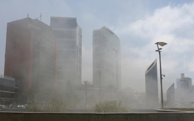 Smoke from Larcomar mall partially obscures buildings nearby, including JW Marriott Hotel Lima, during a fire at the mall where at least three people died, according to the fire department, in Lima