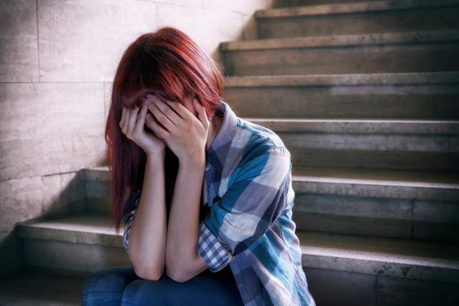 Depressed Girl Covering Face With Hands And Sitting On Steps