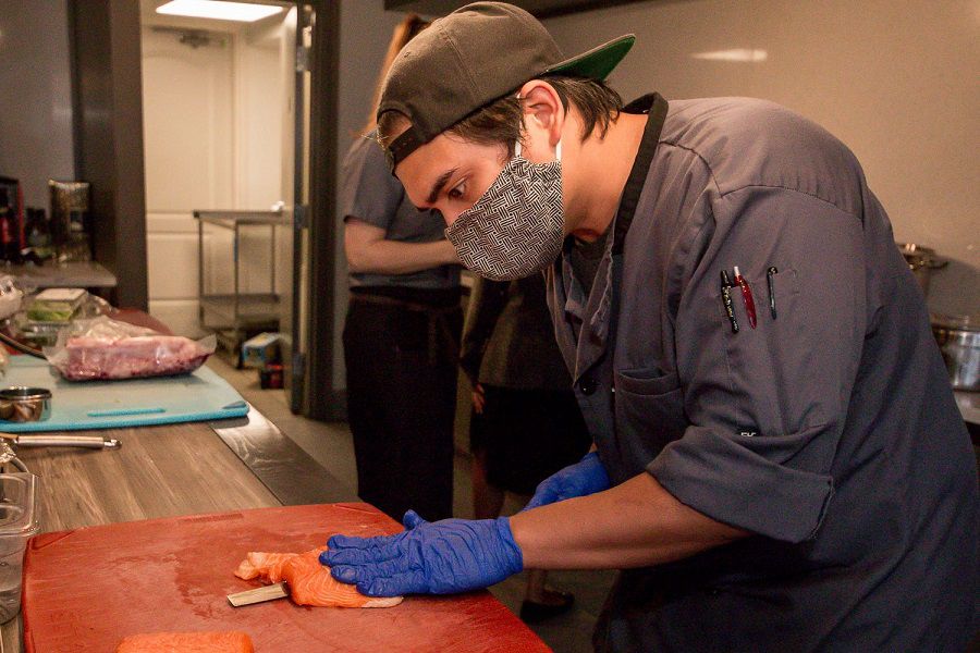 Bonsai sushi cook Rowell Javier slices salmon for an order of sashimi on Wednesday, May 20, 2020. The restaurant opened recently