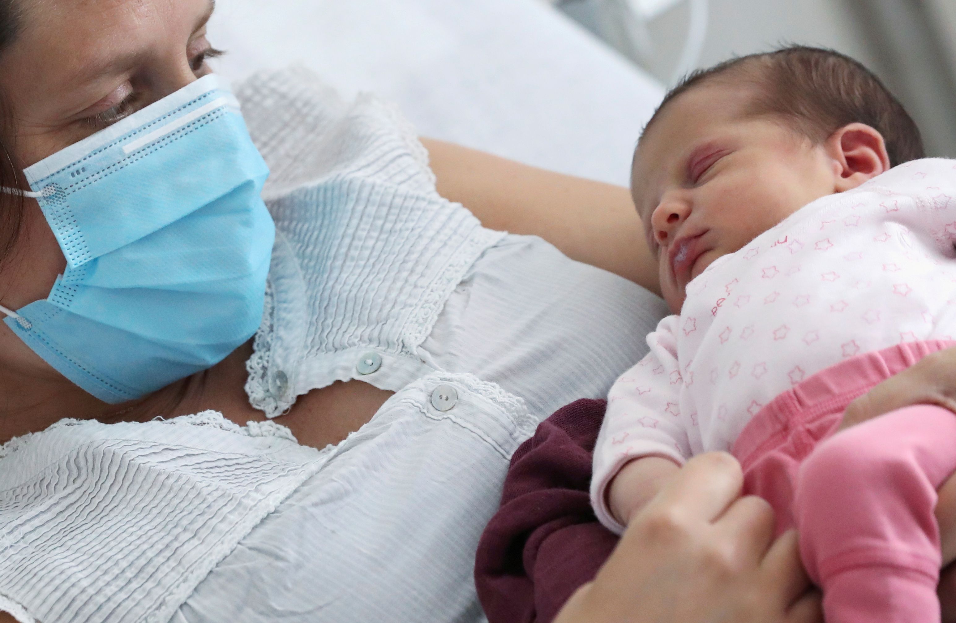 Amandine, who tested positive for the coronavirus disease (COVID-19) just before giving birth, wears a protective face mask while holding her newborn daughter Mahaut at the maternity at CHIREC Delta Hospital in Brussels