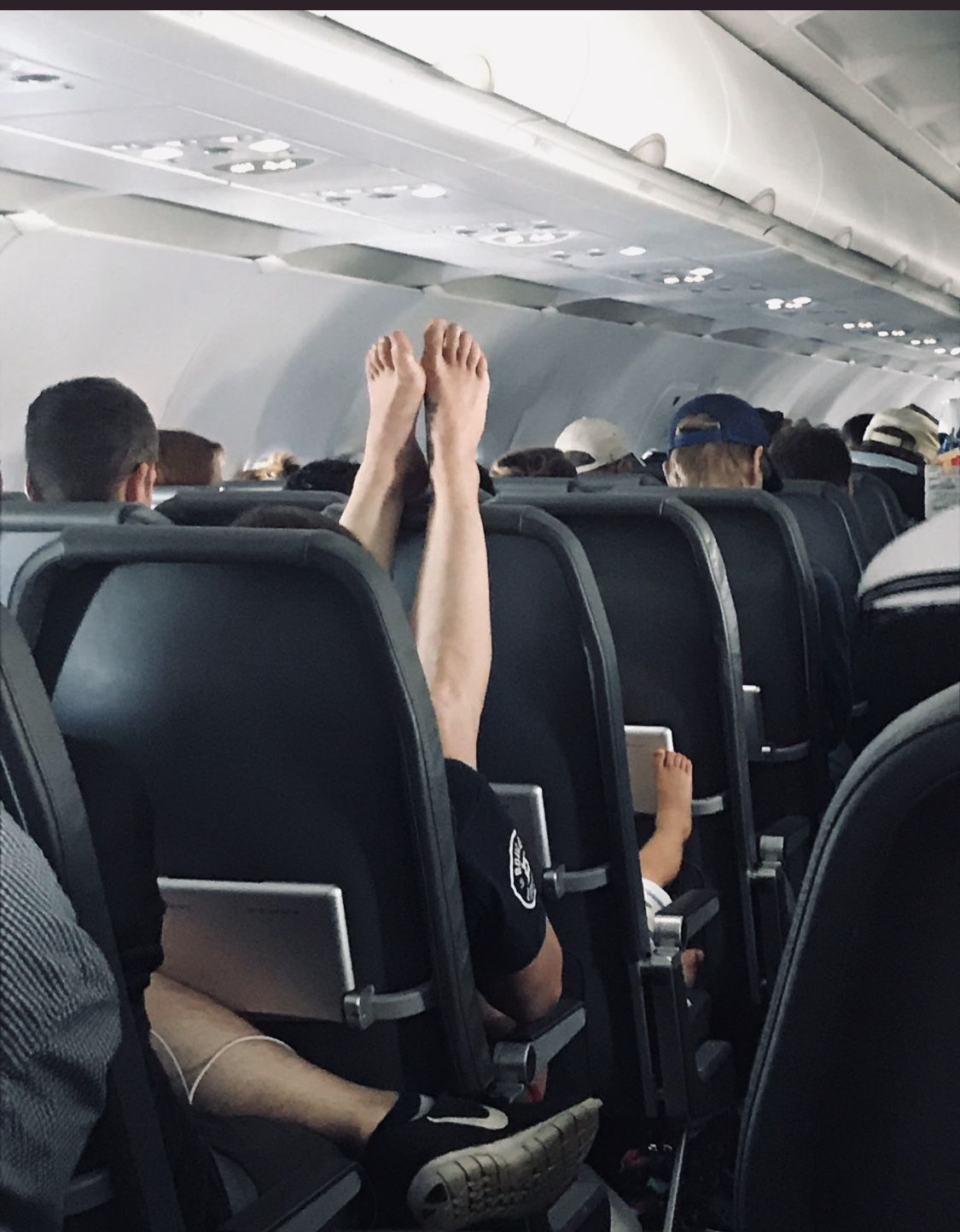 Airplane Passenger Puts Bare Feet On Tray Table - Travel Noire