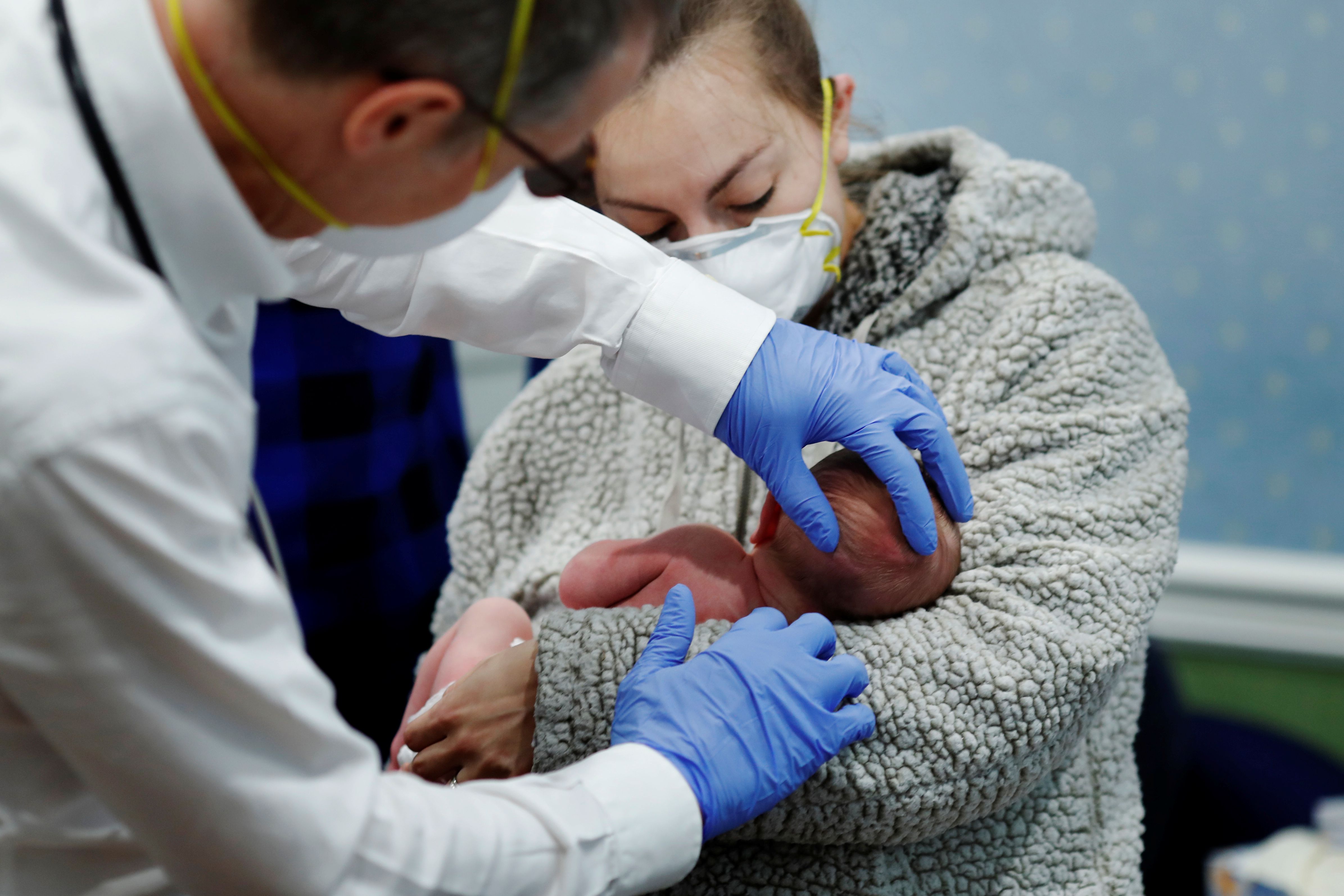 Dr Greg Gulbransen speaks with the parents of a 2-day-old newborn while maintaining visits with both his regular patients and those confirmed to have the coronavirus disease (COVID-19) at his pediatric practice in Oyster Bay, New York