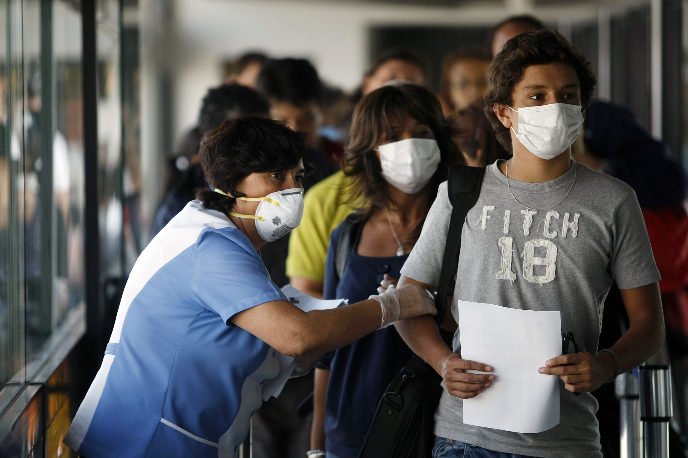 File photo of a health worker wearing a mask monitoring passengers at Santiago's international airport arriving from Mexico