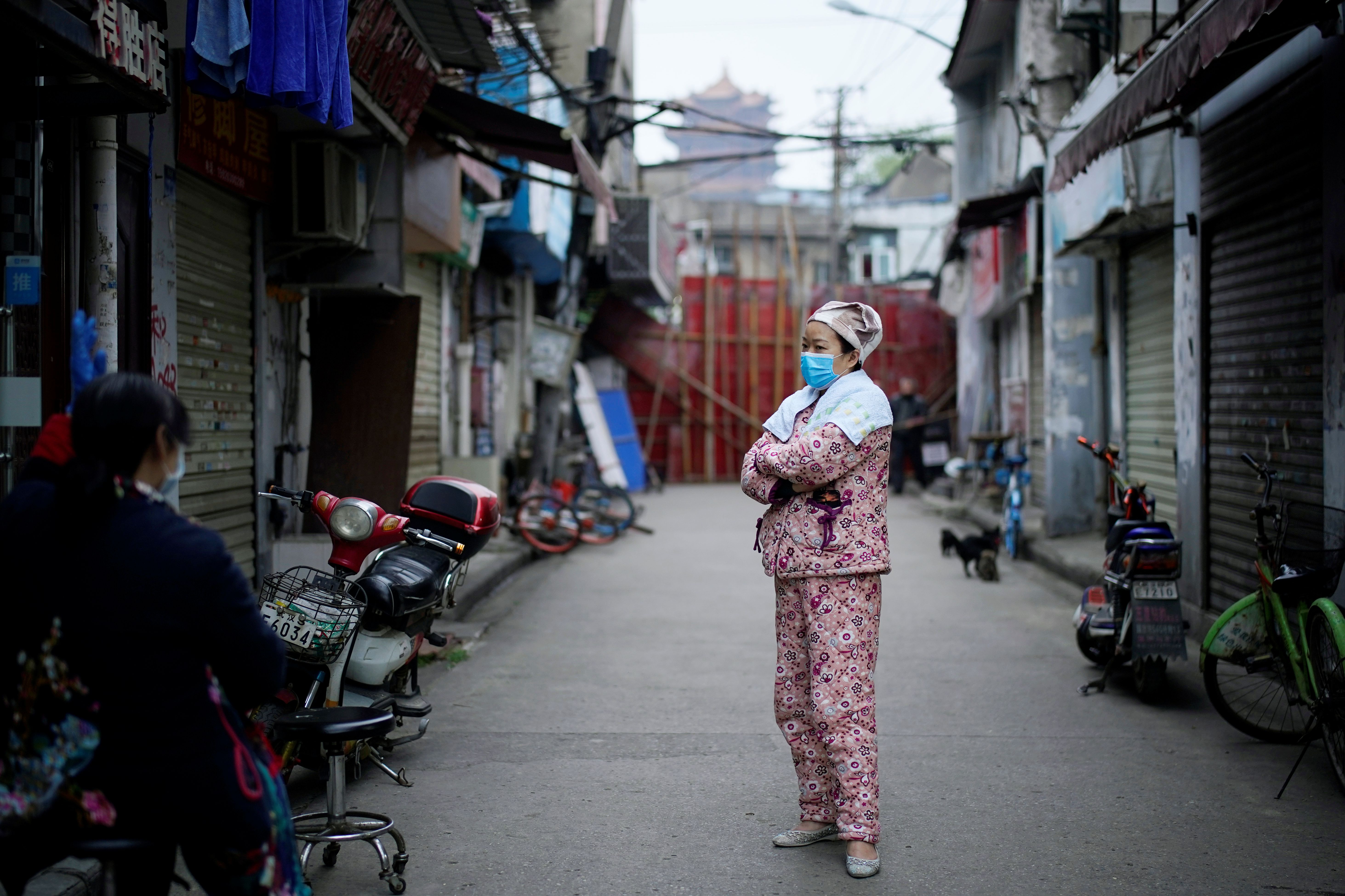 A resident wearing a face mask is seen at an old residential community blocked by barriers in Wuhan