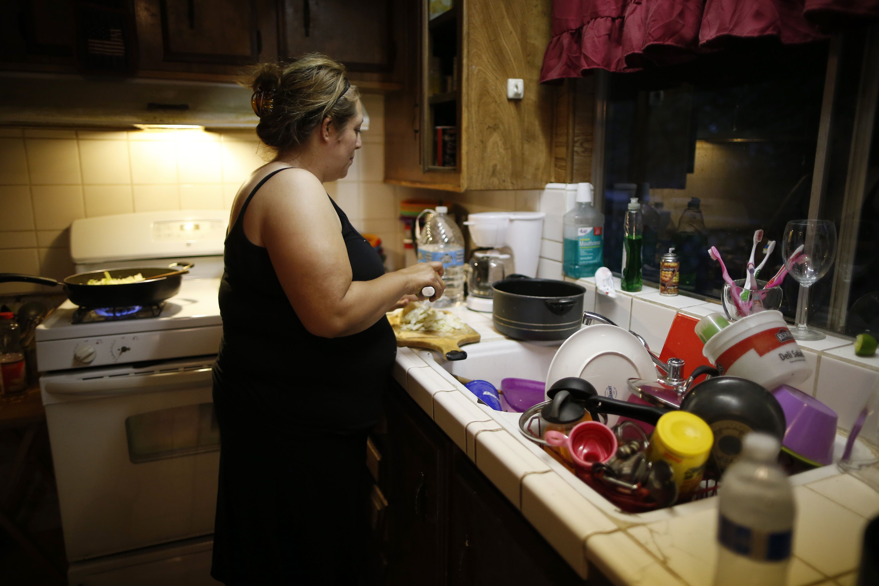 Angelica Gallegos, whose well has run dry, chops vegetables as she stands next to her sink where she washes dishes with bottled water in Porterville