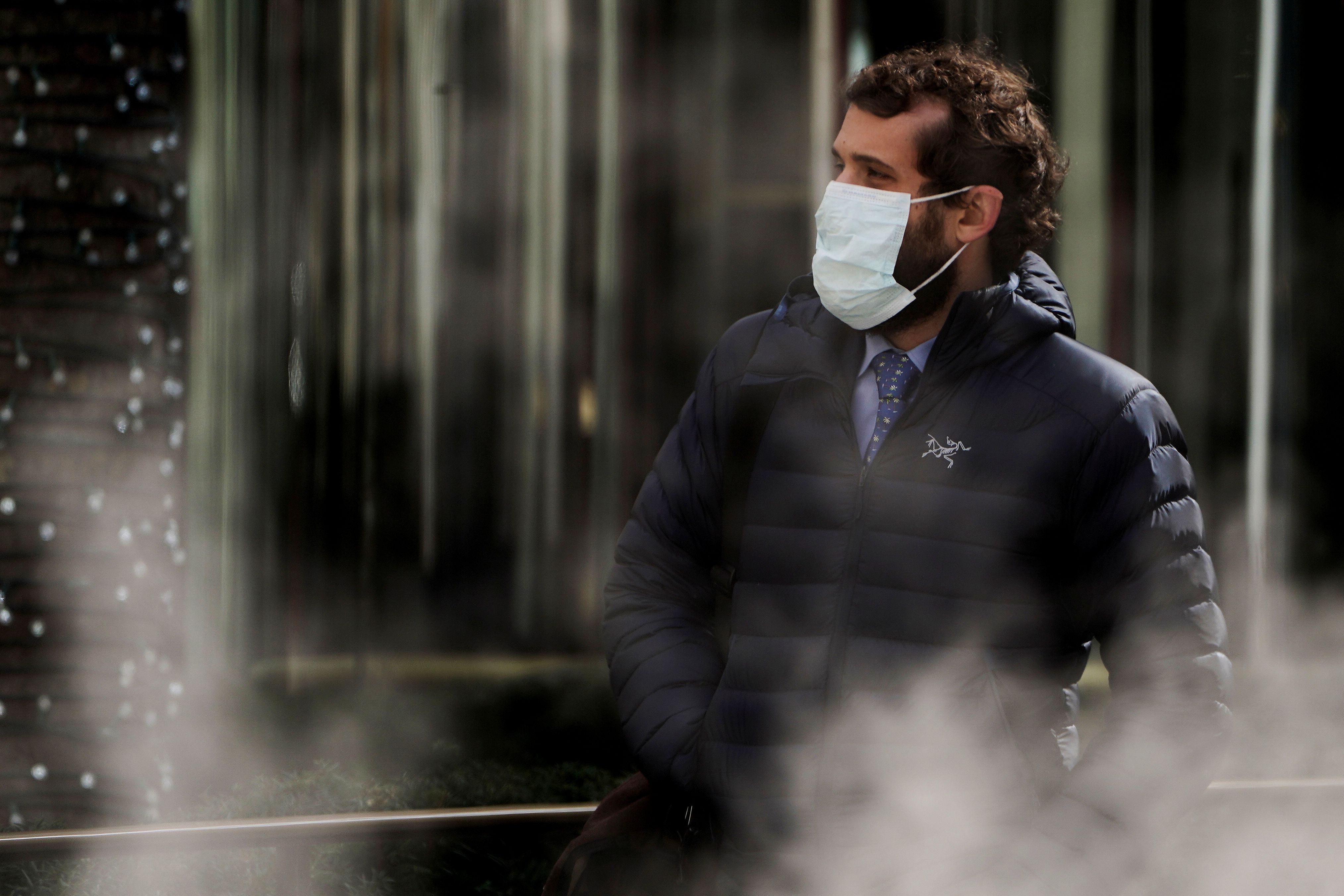 A man wearing a protective mask walks past a steam vent following the outbreak of coronavirus disease (COVID-19), in the Manhattan borough of New York City, New York